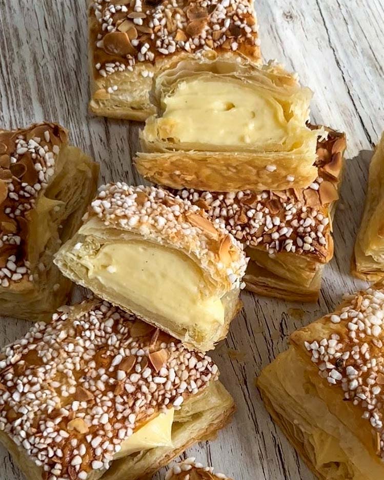 Budapestbakelse med kokosgrädde och jordgubbar 10 Frasiga bakelser med vaniljkräm och socker på toppen, skurna i bitar.