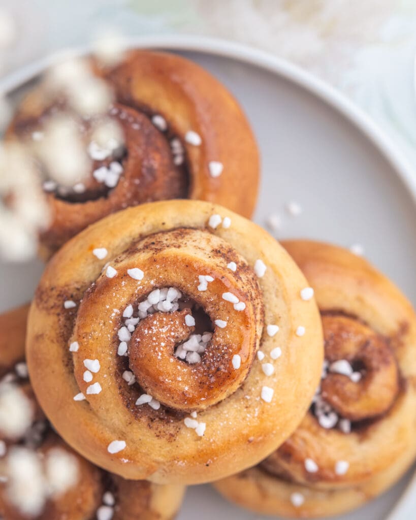 Kardemummabullar med sockerlag 8 Tre kanelbullar med socker på toppen, placerade på en grå tallrik.