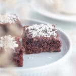 En bit chokladkaka med glasyr och kokosflingor på en tallrik.