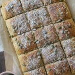 Morotsbröd skuret i fyrkantiga bitar, toppat med pumpakärnor och mjöl.