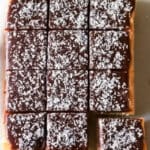 En sockerkaka med chokladglasyr och kokosflingor skuren i bitar.