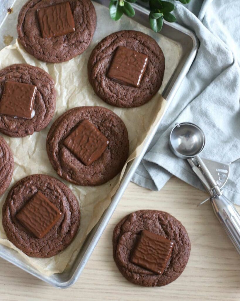 Kokoscookies 9 Mjuka chokladkakor med en After Eight-chokladbit på toppen, placerade på en plåt.