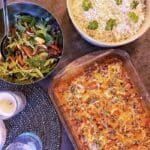 En italiensk fläskfilégratäng serverad med ris och en grönsallad i skålar.