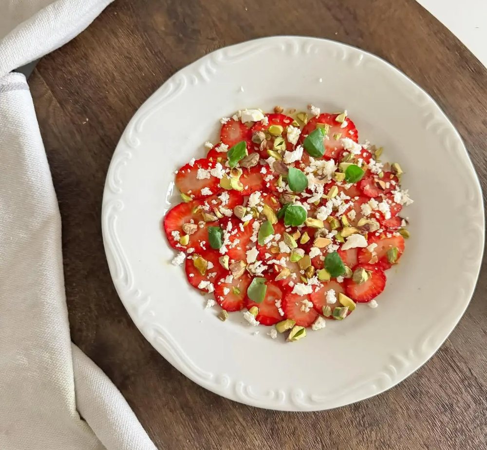 Fikon carpaccio 9 En tallrik med jordgubbscarpaccio toppad med nötter och ost.