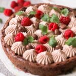 Chokladtårta dekorerad med spritsad grädde, hallon och chokladpraliner.
