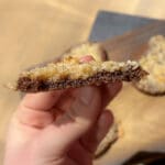 En person håller en kaka med chokladbotten och kokosfyllning i handen.