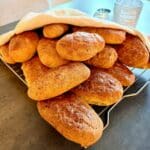 En hög med nygräddade morotsbröd på ett galler, täckta med en kökshandduk.