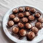 En tallrik med små tiramisu-krustader dekorerade med kakao och grädde.