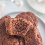 En närbild av chokladmuffins på en tallrik med en bit av en muffin tagen bort.