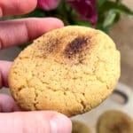En hand som håller en churroscookie med en lätt brun yta och spröd konsistens.