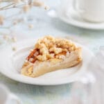 En bit appelkladdkaka med smulor på en vit tallrik, placerad på ett bord.