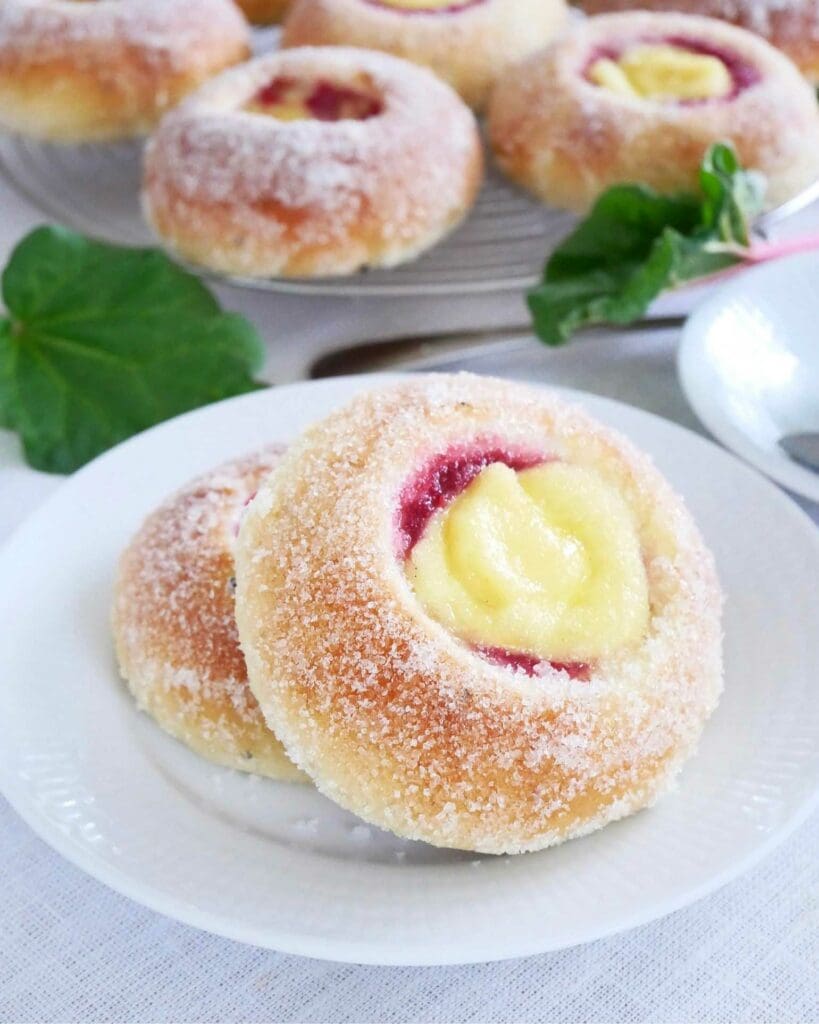 Donuts 11 Två solbullar med rabarberfyllning och vaniljkräm på en vit tallrik.