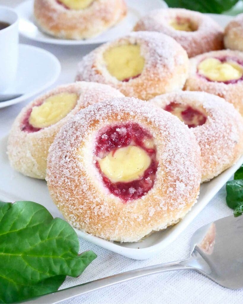 Rabarberkaka 14 Bullar med rabarberfyllning och vaniljkräm på en tallrik, täckta med socker.