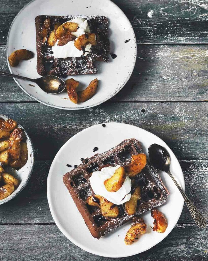 Minibananpannkakor 7 Två portioner chokladvåfflor med äppelkompott och grädde på vita tallrikar.