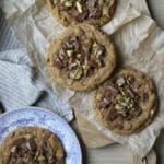 Tre stora kakor med brynt smör och chokladbitar på ett bakplåtspapper.