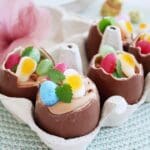 Fyllda kinderägg med chokladfyllning och färgglada godisar på toppen i en äggkartong.