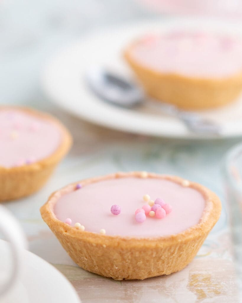 Chokladbollar utan tillsatt socker 5 Glutenfria mazariner med rosa glasyr och färgglatt strössel på toppen.