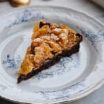 En bit kladdkaka med cornflakes-topping på en vit tallrik med blå dekorationer.