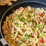 En stekpanna med kramig kebabpasta, körsbärstomater och persilja på toppen.