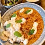 En tallrik med kyckling tikka masala, ris och en skål med sallad.