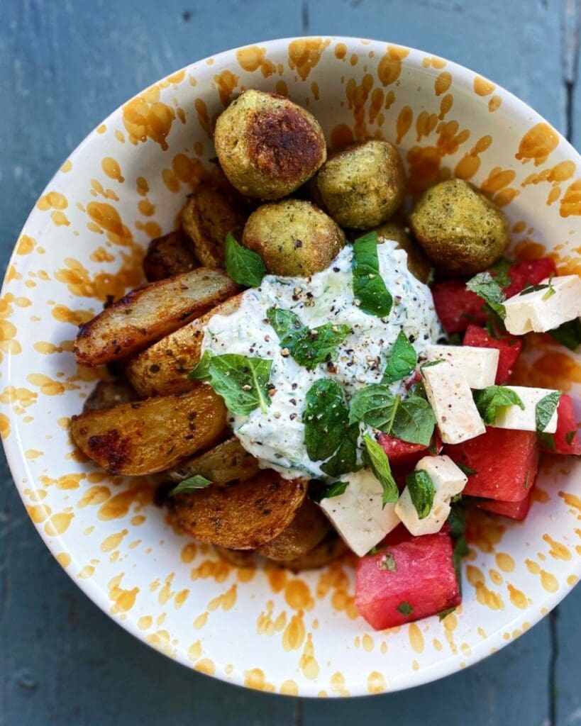 Hot honey halloumi bowl 6 En falafelbowl med potatis, vattenmelon, fetaost och kokostzatziki i en skål.