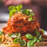 En tallrik med italienska köttbullar serverade på spaghetti med tomatsås och färska örter.