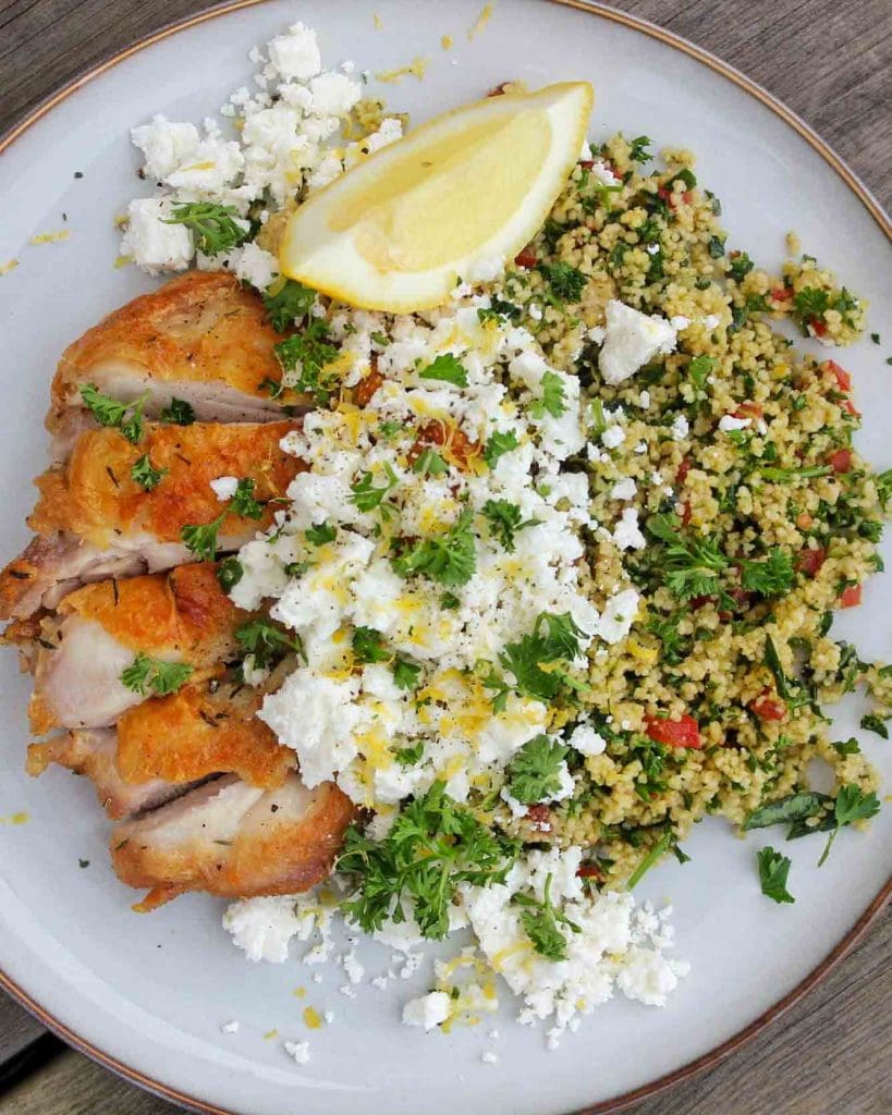 Citronkyckling 6 En portion kycklingstek serverad med couscous, fetaost och citronklyfta på en tallrik.