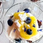 Dessert i glas med grädde, blåbär, citronsås och ätbara blommor.