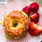 En bagel med gurkskivor och jordgubbar på en tallrik med blommönster.