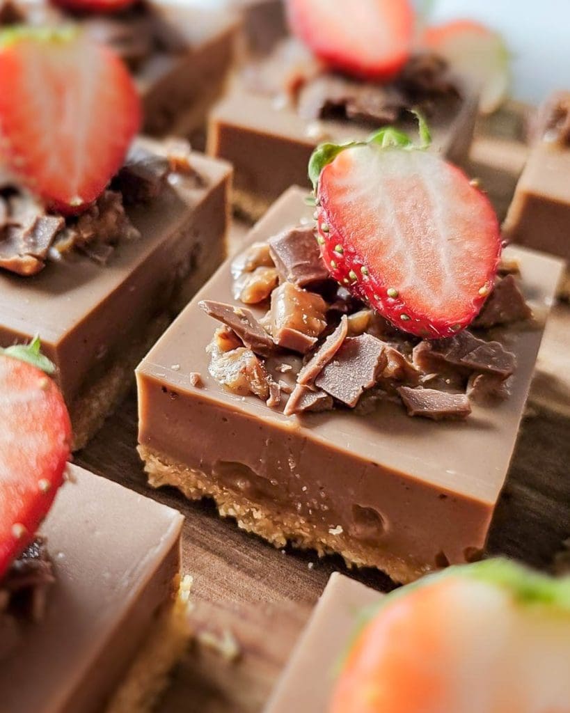 Hallonrutor 9 En närbild av Daim pannacotta rutor med jordgubbar och chokladbitar på toppen.