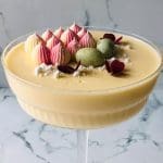 En påskdessert i en glasbehållare med grädde och färgglada dekorationer på toppen.