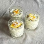 Tre glas med kokoschiapudding toppad med mango, apelsin och kokosflingor.