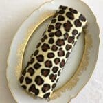 Leopardmönstrad rulltårta med Nutella på en vit tallrik med guldkant.