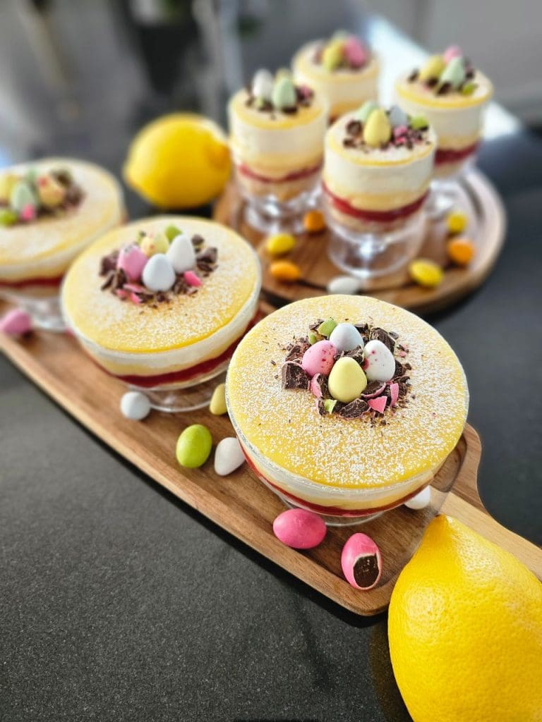 Påskprinsesstårta i glas med lemon curd 8 Paskprinsesstarta i glas med gula och rosa dekorationer samt chokladägg på toppen.