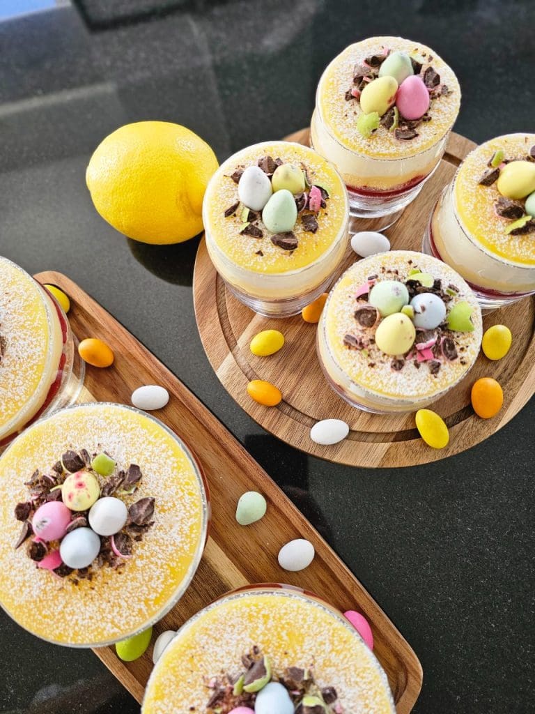 Påskprinsesstårta i glas med lemon curd 9 Paskprinsesstarta i glas med gula och rosa dekorationer samt små chokladägg.