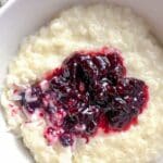 Skål med risifrutti toppad med sylt av bär i en vit skål.