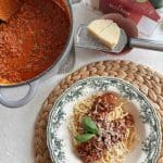 En tallrik med pasta och bolognesesås, toppad med parmesan och basilika.