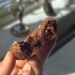 En person håller en chokladbollscookie med en bit tagen ur den.