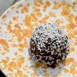 Chokladboll täckt med kokosflingor på en tallrik med orange mönster.