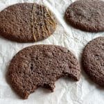 Fyra sega chokladkakor på ett bakplåtspapper, en med en bit tagen ur.