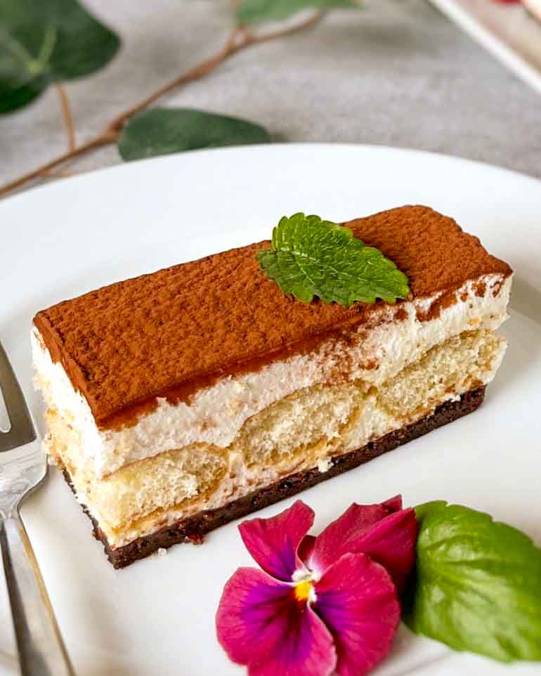 Budapestbakelse med kokosgrädde och jordgubbar 9 Tiramisu bakelse med lager av grädde och kakor, dekorerad med mynta och blommor.