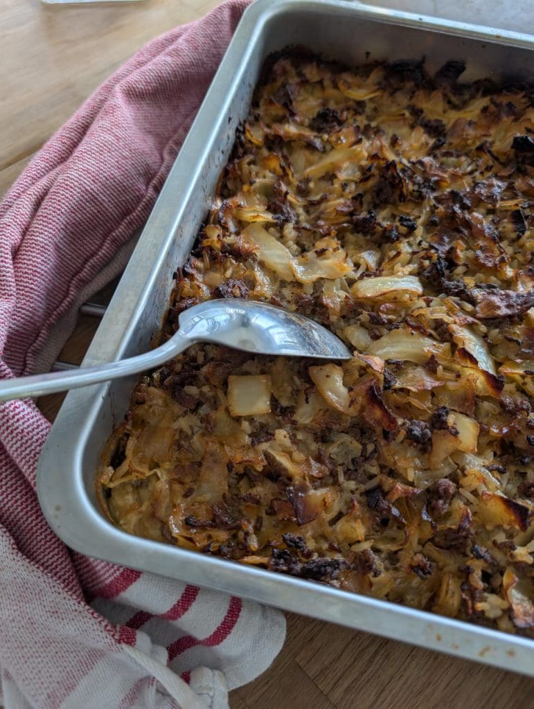 Finsk kållåda - Kaalilaatikko 6 En ugnsform med finsk kåldolmar, innehållande köttfärs och kål, med en sked placerad i formen.