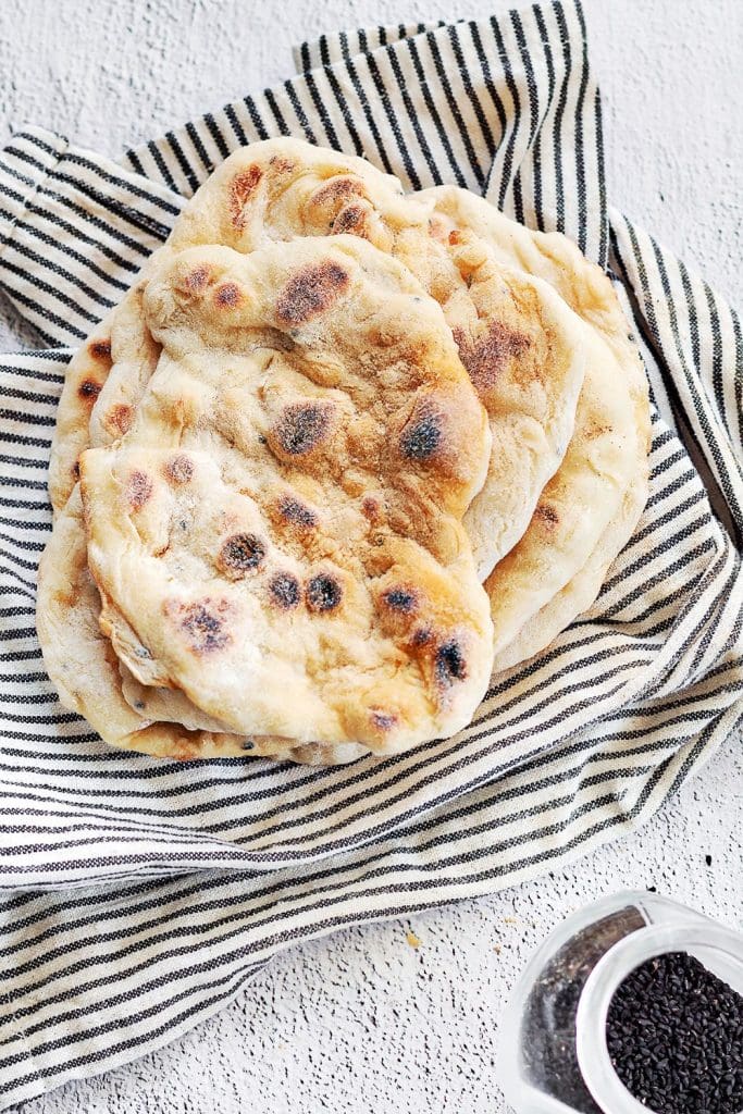 Naanbröd 6 En hög med hembakat naanbröd på en randig kökshandduk.