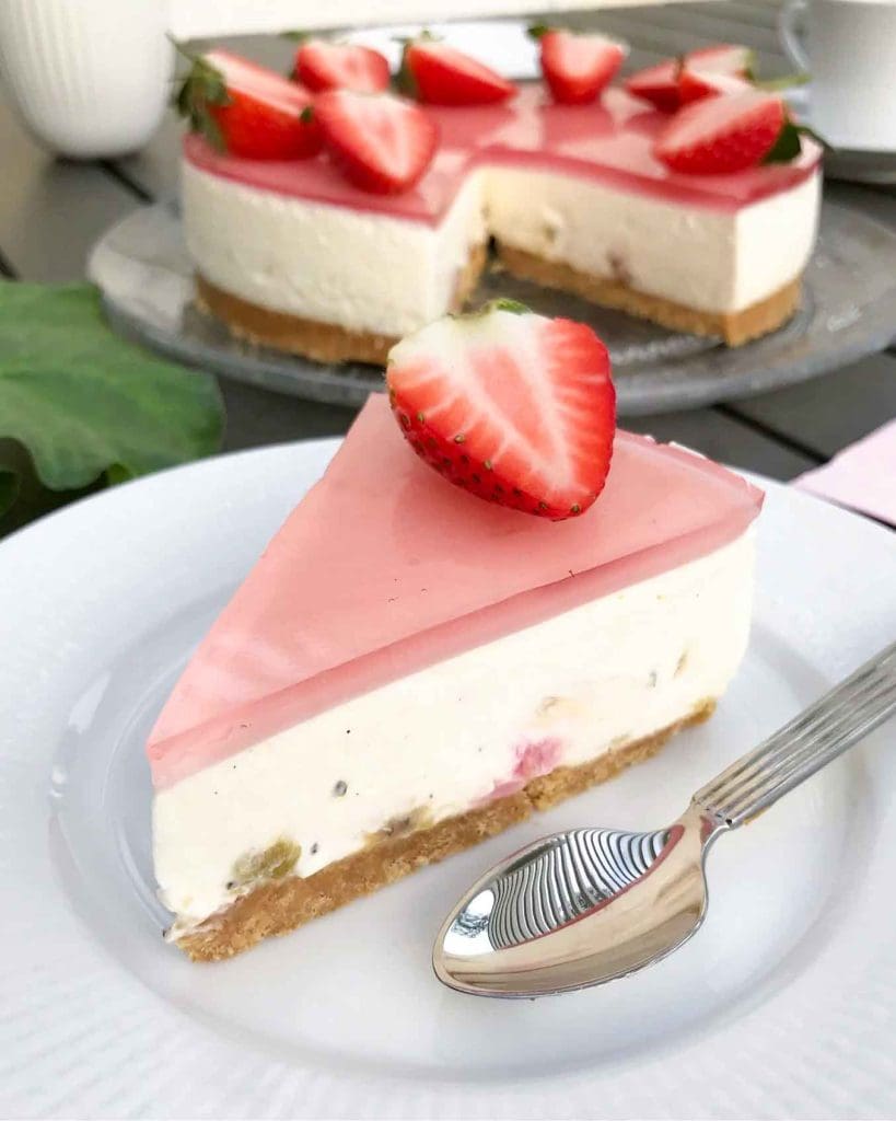 Knäckig rabarberpaj med en touch av fläder 10 En bit rabarbercheesecake med jordgubbar på toppen, serverad på en tallrik.