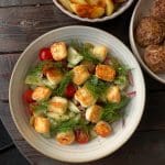 En tallrik med sallad innehållande halloumi, tomater, gurka och dill.