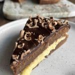 En bit fransk chokladtårta med smörkräm och dekoration av chokladspån.