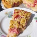 En bit jordgubbskladdkaka med smuldeg på en tallrik med blommönster.