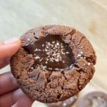En hand som håller en kaka med chokladfyllning och havssalt på toppen.