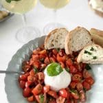 En skål med tomatsallad, burrata och surdegsbröd på en tallrik.