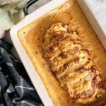 Ugnsbakad hasselbacksfläskfilé i en vit ugnsform med gyllenbrun yta.